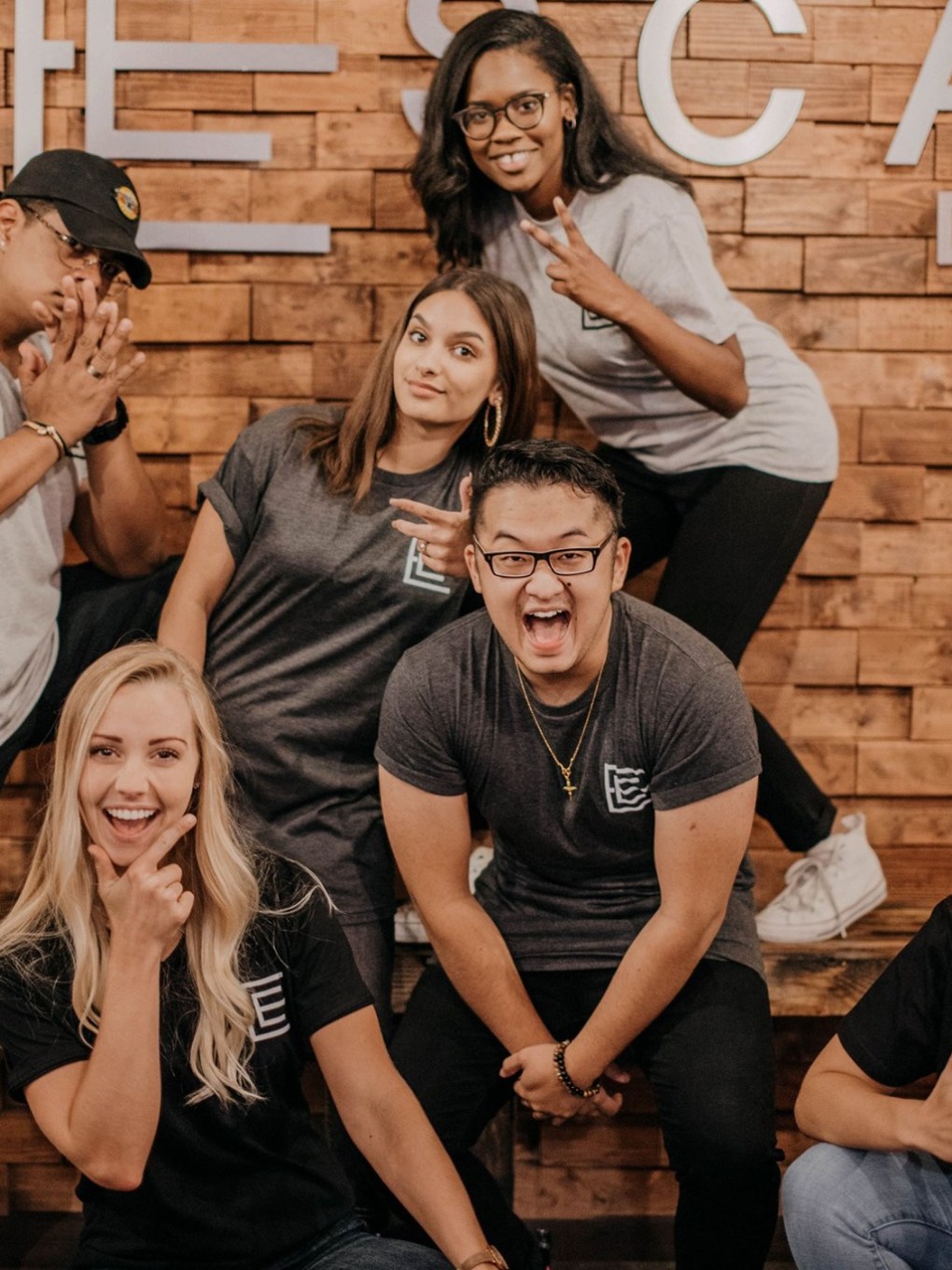 a group of people posing for a photo in front of a brick wall