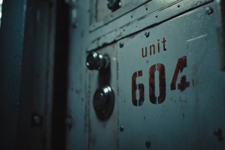 Close-up of a metal door with the text 'unit 604' in dim lighting.