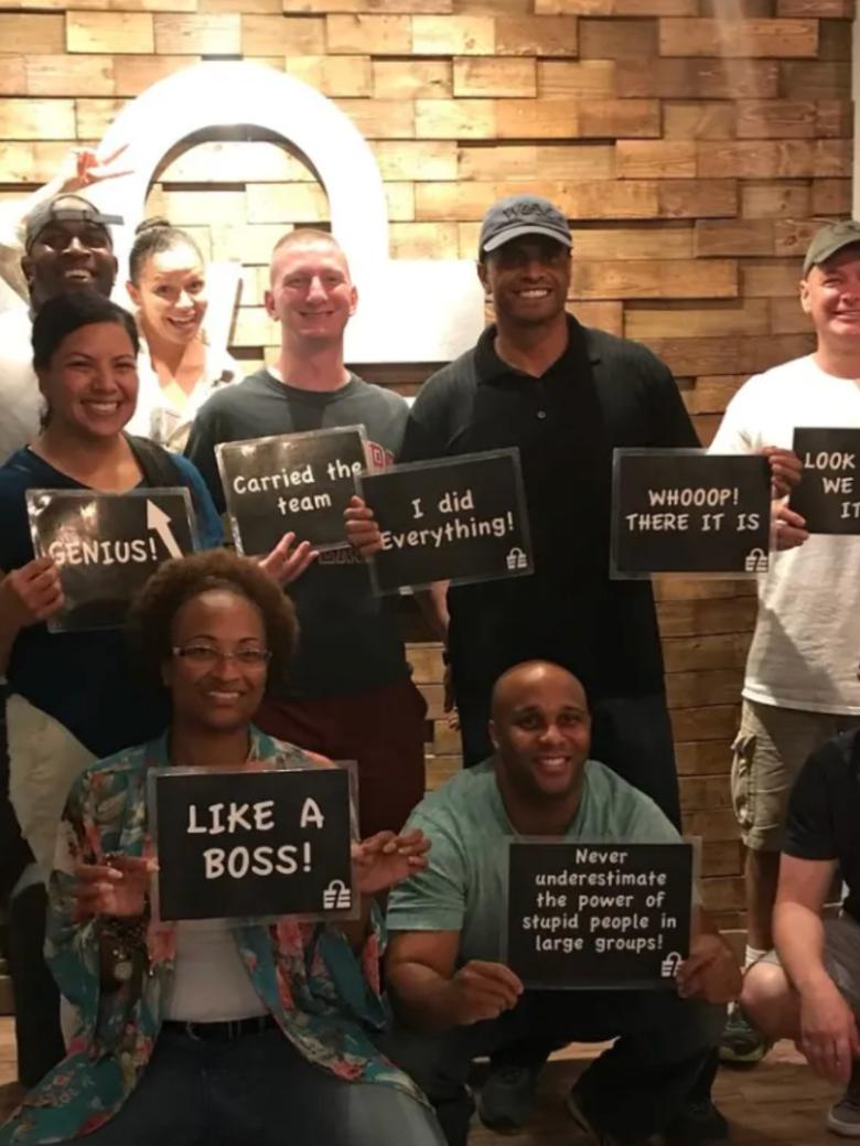 Group of people smiling and holding signs at Huntsville Escape Rooms.
